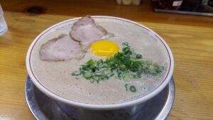 創業63年という福岡を代表する老舗の豚骨ラーメン店《博多だるま 5号線 筑紫野市塔原西店》が昨年の12月に開業したと聞いて早速行ってきました！

駐車場が半端なく広いのですが、少し奥に止めたにも関わらず、食欲をそそる熟成の進んだ豚骨の薫りが漂ってきて期待に胸が膨らみます😊

歴史を継ぐ総本店の味を本当に食べれるのかとドキドキしながら暖簾をくぐり《博多だるま 総本店》でも、いつも注文している「月見ラーメン950円」を選択し、麺の硬さは、勿論「バリカタ」で！

程なく（小ぶりの器にナミナミと注がれた豚骨のスープのため）スタッフの方が、ゆっくり丁寧に配膳した「月見ラーメン」は、泡立つ脂が表面を覆い、その中央あたりに卵黄を配した様子が、雲海に浮かぶ満月のようなコントラストで《博多だるま 総本店》とも、ほとんど遜色のない見た目😚

このクリーミーな泡がたまらんとです！

シャバシャバとした印象のある豚骨スープは、濃度が高めで脂泡もたっぷり。ひと口スープを啜ると熟成感もありつつ旨みあふれるヴィンテージな味わいに仕上がっていて、もうレンゲが止まりません(笑)

そして何よりテーブルに置いてある『お酢』があるのですが、ただのお酢ではないのです！

豚骨ラーメンの罪悪感を消してくれる『老化防止』アイテムなのです😁

①血糖値の急上昇(スパイク)を抑えてくれる
②脂肪の燃焼分解を助けてくれる
③塩分の排出をサポート

などなど嬉しい効果があるのに、更にラーメンを美味しくしてくれちゃいます！

もうこの言葉に甘えてダメだダメだと思いつつも、いつもレンゲでスープを『この一杯で最後にしよう』『あと2杯だけ』と思いつつもスープを飲み干しちゃってます😂

途中、味変として月見（卵黄）をレンゲに乗せて溶きつつ、塩味の効いたスープとともに麺や具材と一緒にいただくと相性抜群。至福のひと時が楽しめる一杯に！

ちなみに僕は途中から紅しょうが3杯、ゴマ、お酢を2プッシュ、ニンニクを2個これを少しずつ追加しながら更なる味変をして楽しんでおります😚

合わせる自家製の極細ストレート麺を持ち上げると上澄みの脂泡とスープがしっかり絡んできて極上の美味しさを楽しむことができる。歯切れの良さとともに食感も心地よく、あっという間に完食。ごちそうさまでした。《博多だるま 5号線》おすすめです！

ちなみに美味しすぎて麺があっという間になくなっちゃいます(笑)

共有駐車場97台分を完備してるので、結構余裕もって車も止めれちゃうので、そこも何気に嬉しいところです😊

やっぱり駐車場が止めづらいと足が遠退いちゃうのて、こういう大きくて止めやすい駐車場は、何気に嬉しいです！

博多だるま 5号線

住所　　｜福岡県筑紫野市塔原西1-1-6

営業時間｜11：00～22：00（L.O. 21：30）

定休日　｜年中無休　※要確認

#博多だるま
#筑紫野
#筑紫野市
#福岡ラーメン
#筑紫野グルメ
#福岡
#福岡県
#筑紫野ラーメン
#筑紫野市ラーメン
#ラーメン
#グルメ
#福岡グルメ
#福岡県グルメ
#筑紫野市グルメ
#福岡ランチ
#福岡県ランチ
#筑紫野ランチ
#筑紫野市ランチ
#ランチ